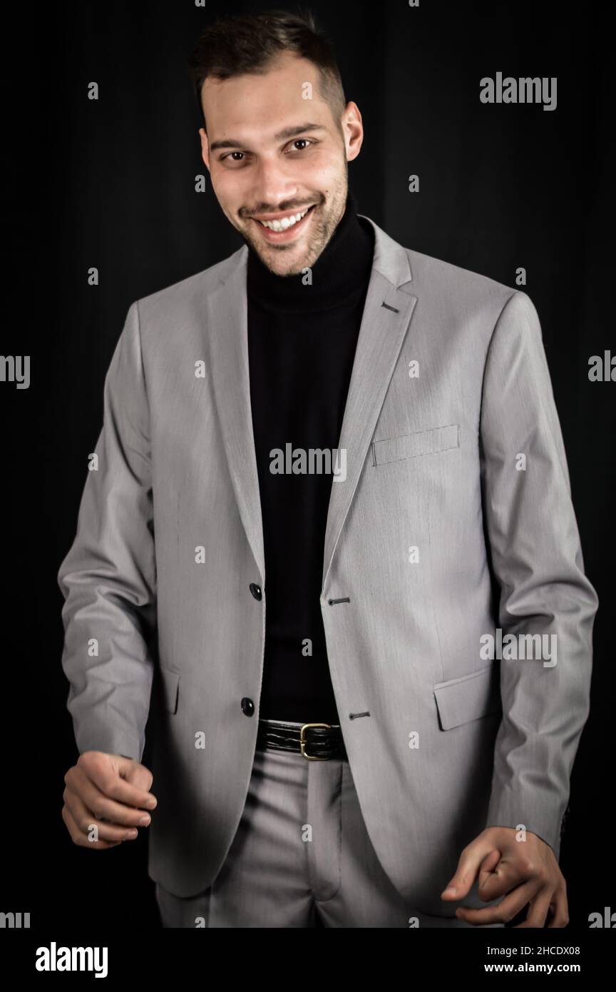 portrait of a young businessman in a gray suit who smiles but shows some embarrassment with his hands Stock Photo