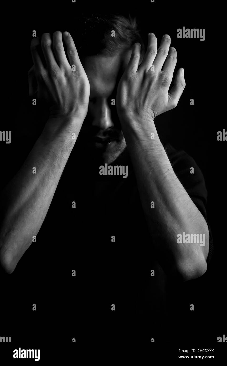 black and white portrait of a young man covering his eyes with his ...