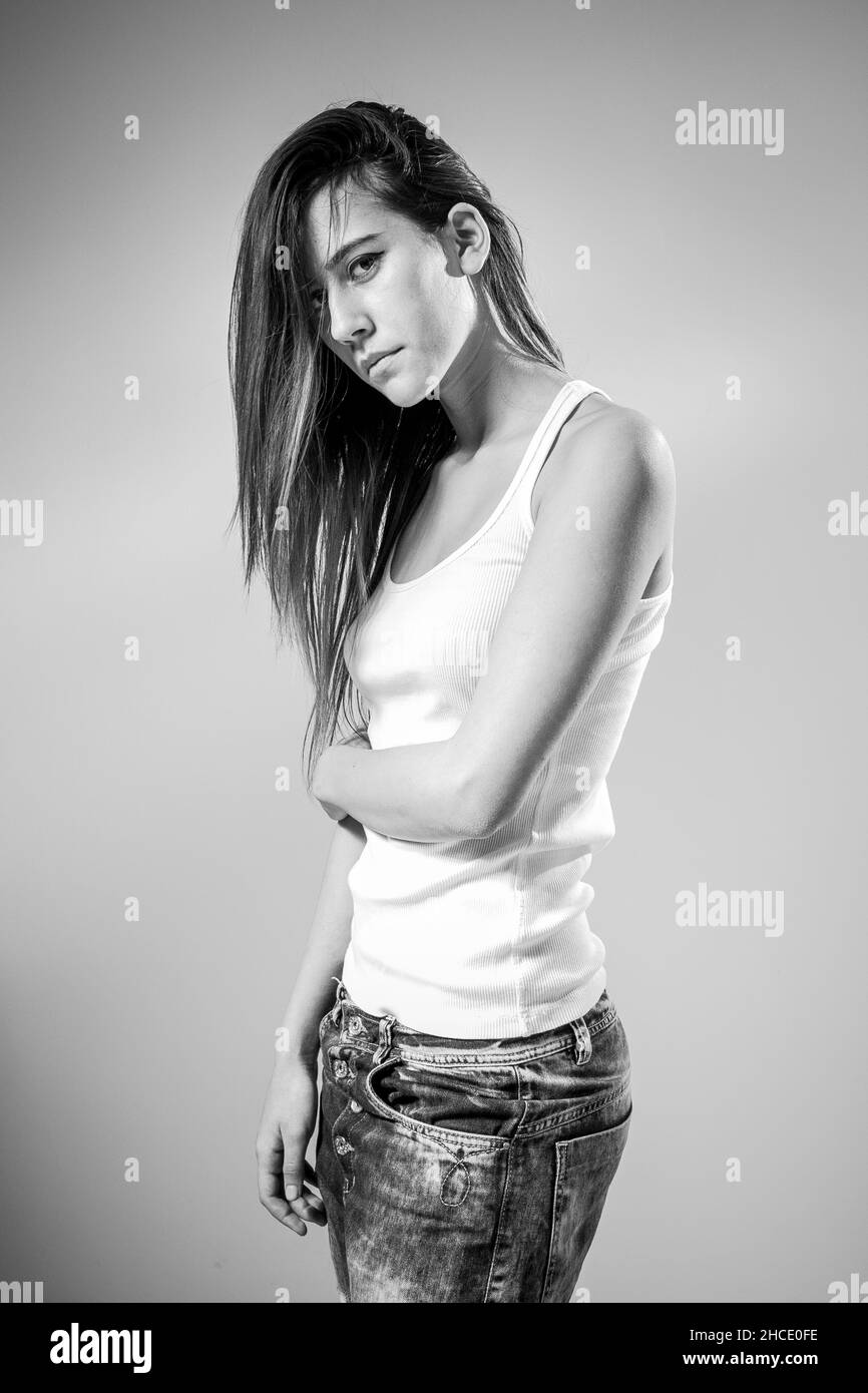 Young teen with long straight hair in jeans and tank top in black and white Stock Photo