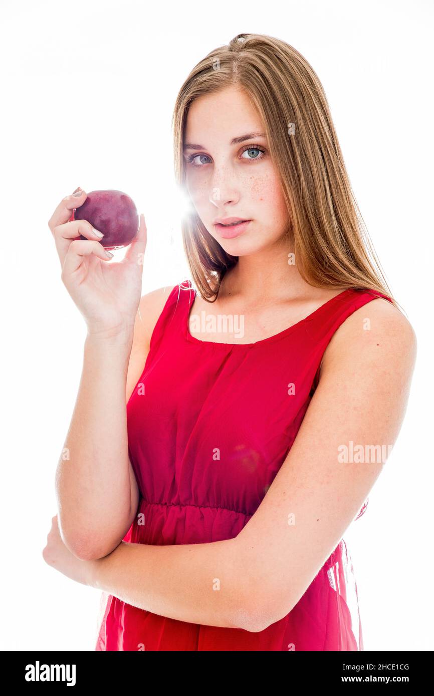 young 19 year old hip and fashionable teen with a red dress and apple in a studio Stock Photo