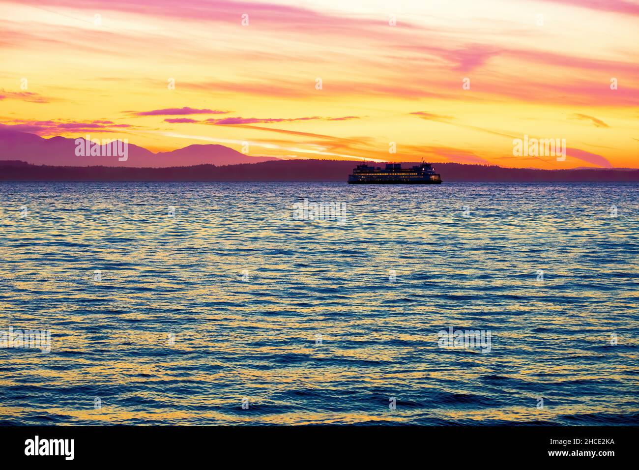 Large ferry boat sailing across water at sunset Stock Photo