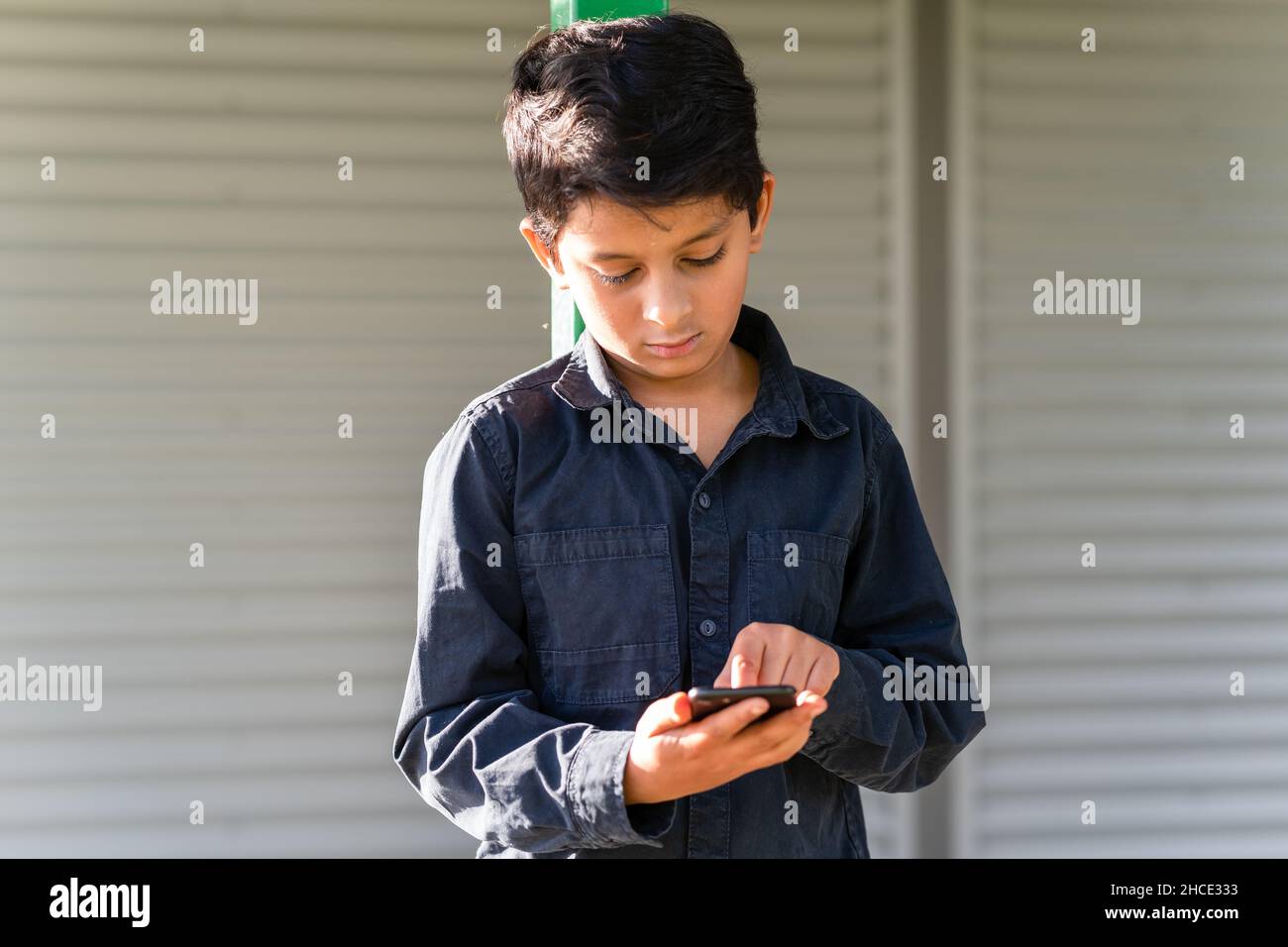 Young boy preteen using mobile phone. Child tapping on cell phone screen. Stock Photo
