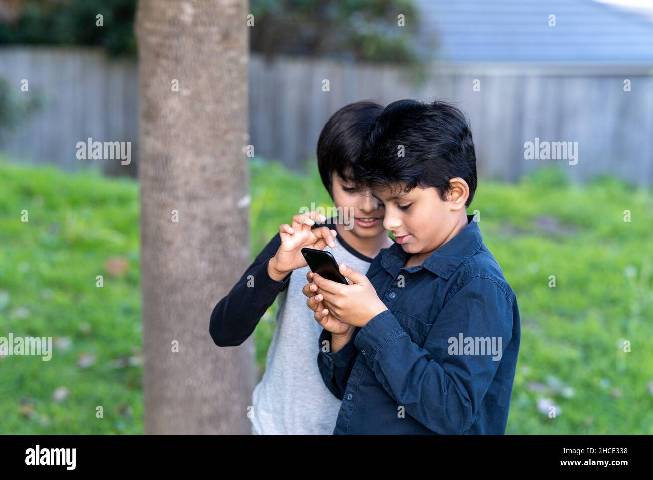 Two young kids using mobile phone. Curious children looking at mobile phone. Stock Photo