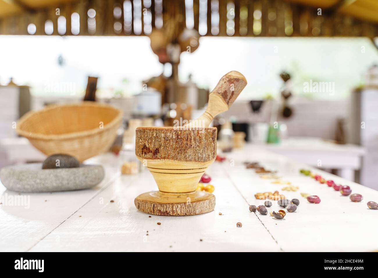 Wooden mortar and pestle placed against coffee berries and beans on