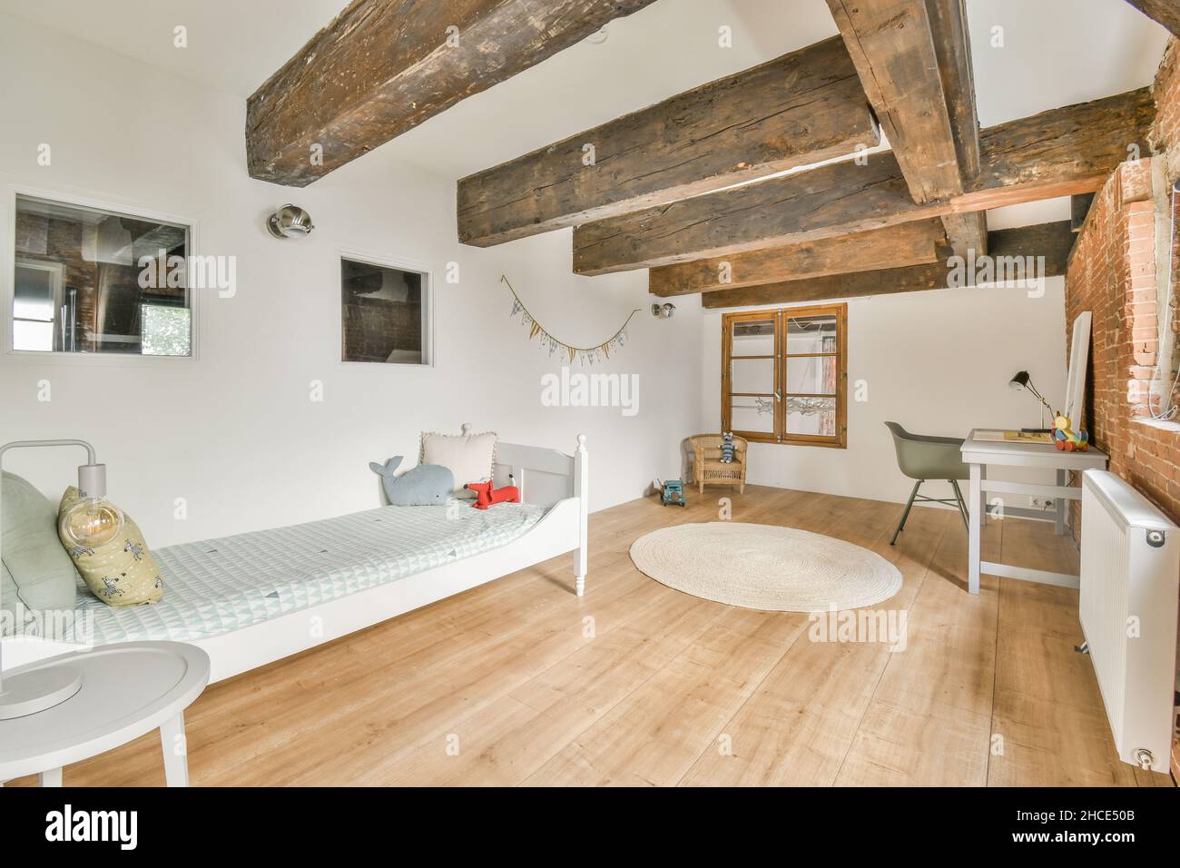 Stylish interior of spacious bedroom with brick wall furnished with bed