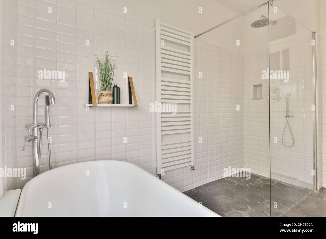 White ceramic bathtub with faucet placed at tiled wall with towel