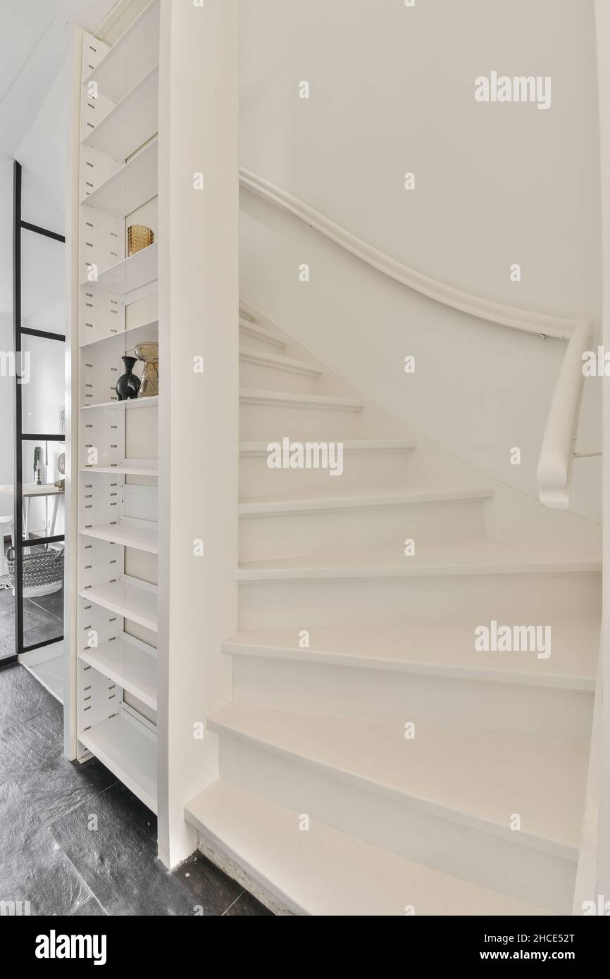 Corridor with white staircase and railing placed near various ...