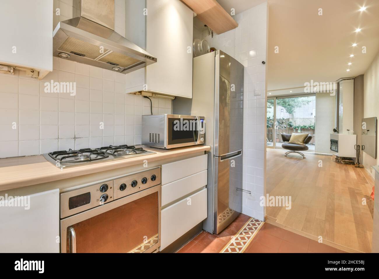 Interior of contemporary kitchen with cabinets and counter opposite fridge and stove with range hood Stock Photo