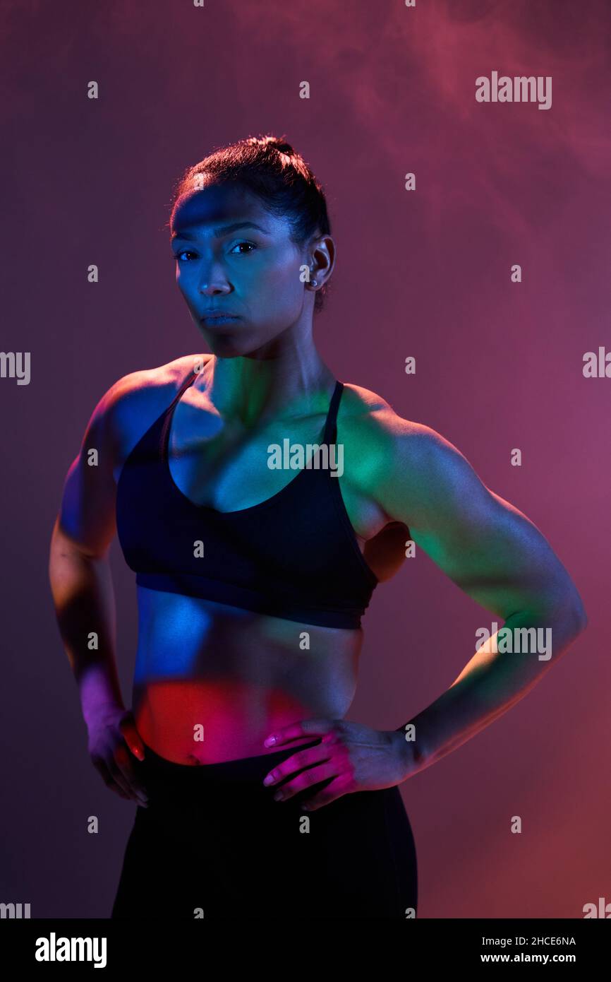 Confident slim female athlete in sportswear standing with hands on hips ...