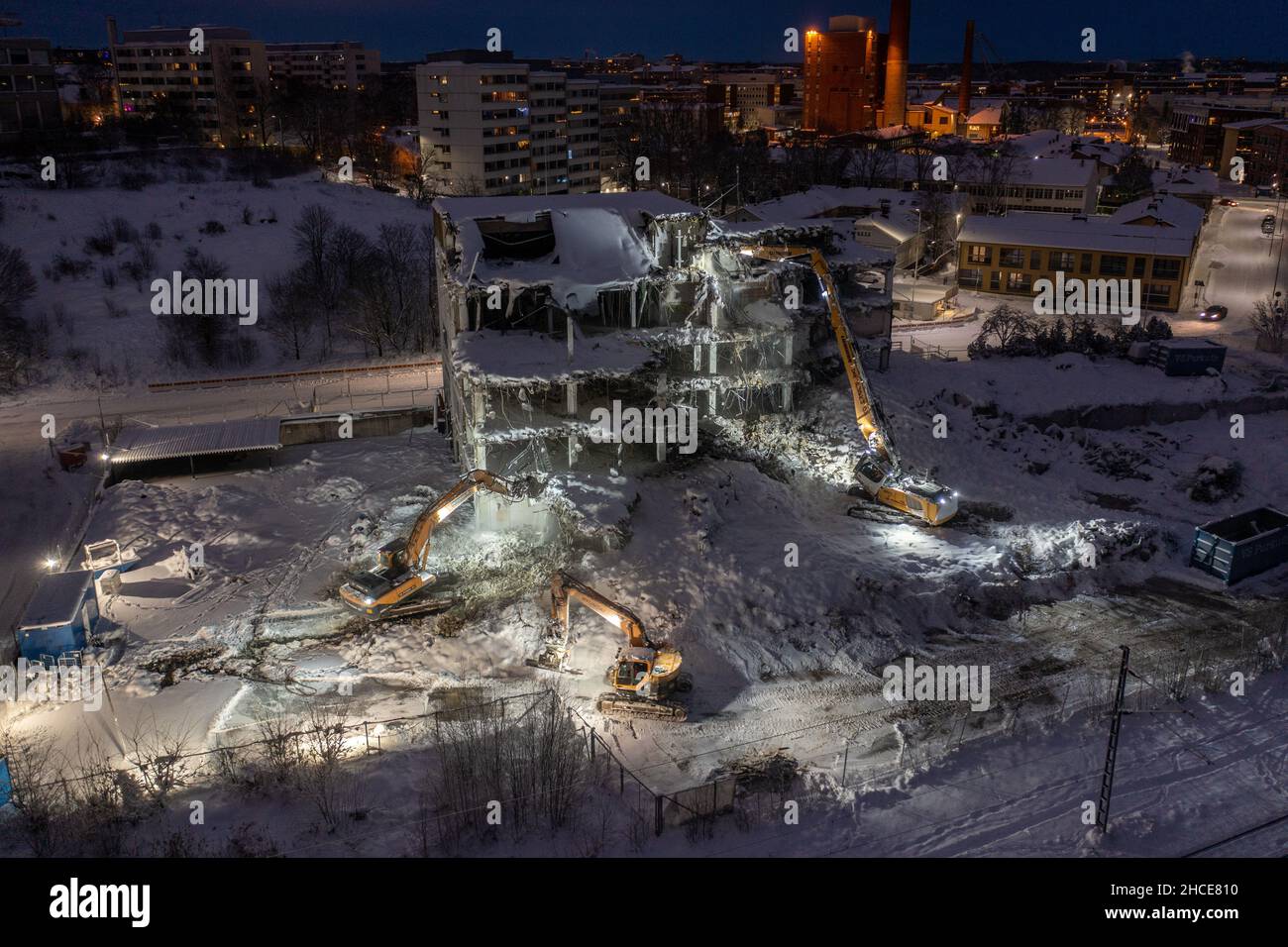 Turku, Finland - December2021: Aerial view of a building demolishing work by excavators in winter night. Stock Photo