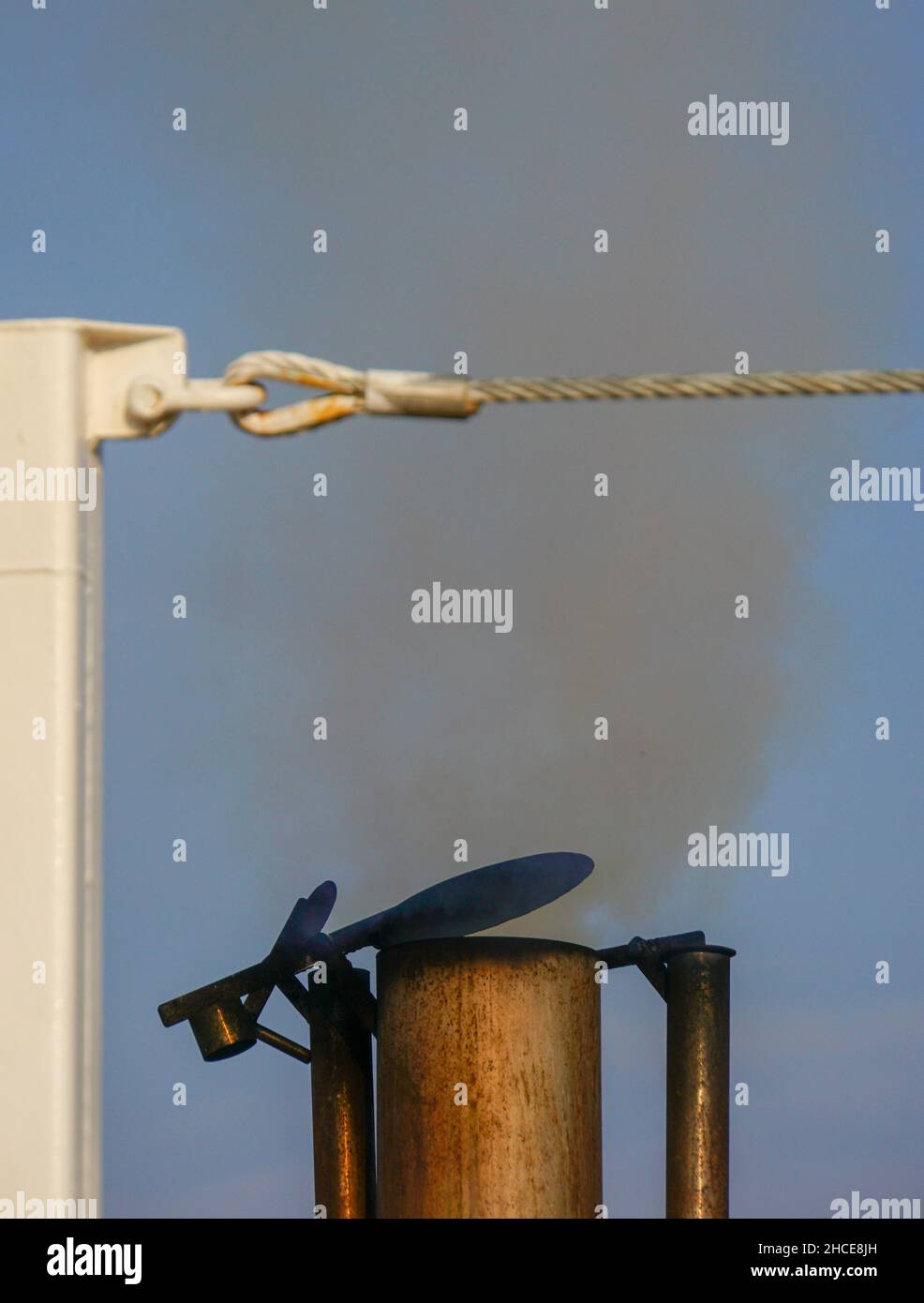 exhaust pipe emitting smoke and fumes from an old maritime diesel engine on a fishing boat Stock