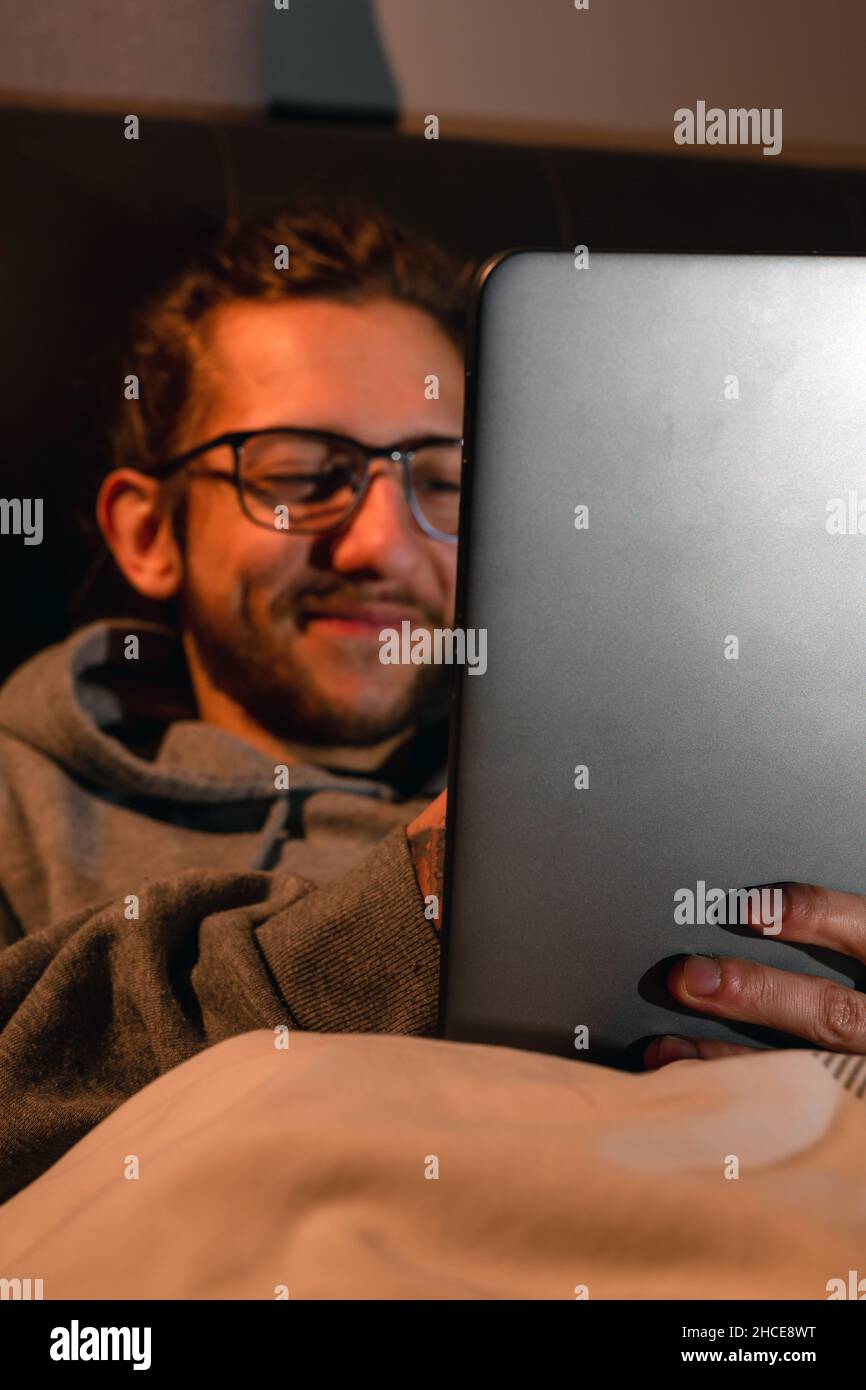A young man using a tablet in bed before going to sleep. Addiction