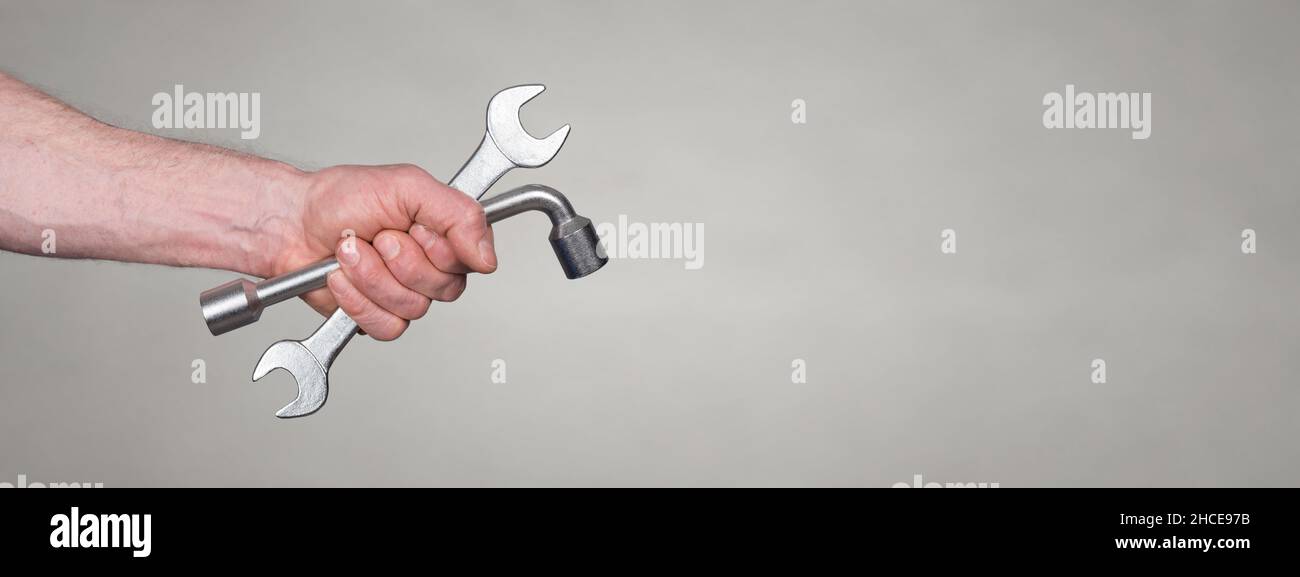 Hand of mechanic holding wrenchs on blurred background Stock Photo - Alamy