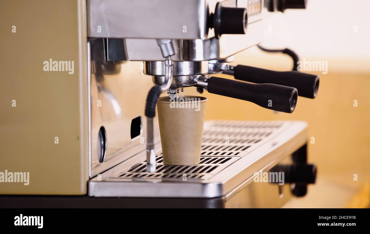 professional coffee maker pouring drink in paper cup in modern coffee ...