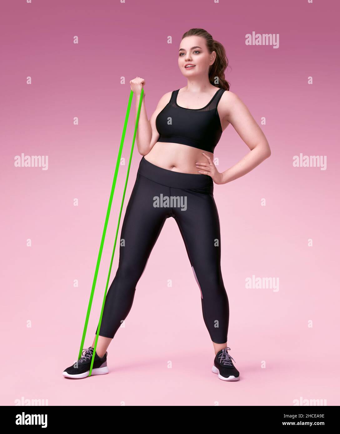 Strong girl working with resistance band. Photo of model with curvy figure  in fashionable sportswear on pink background. Sports motivation and healthy  Stock Photo - Alamy