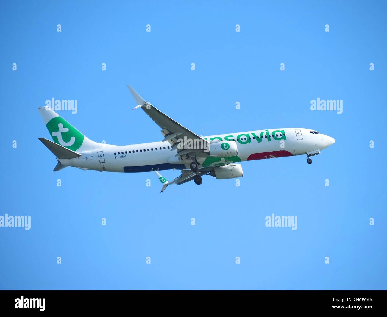 Transavia airplane with green logo flying at blue sky Stock Photo
