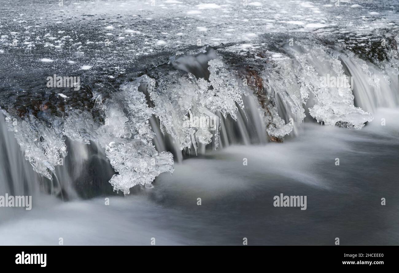Frozen river cascade with icicles, long exposure photo Stock Photo
