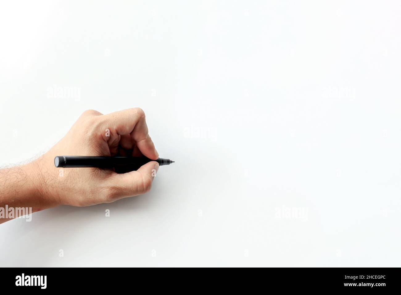 man's hand holding a pen writing on white background. space for text ...
