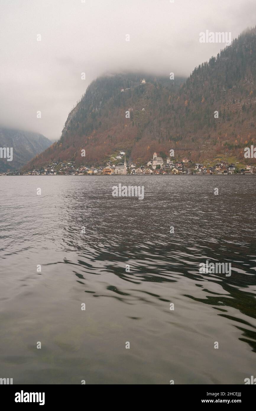 Vertical shot of a calm lake with houses in the background under a ...