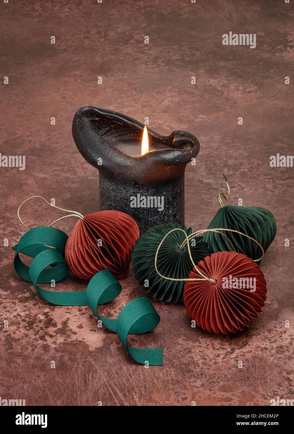 Thick black candle and four paper baubles Stock Photo