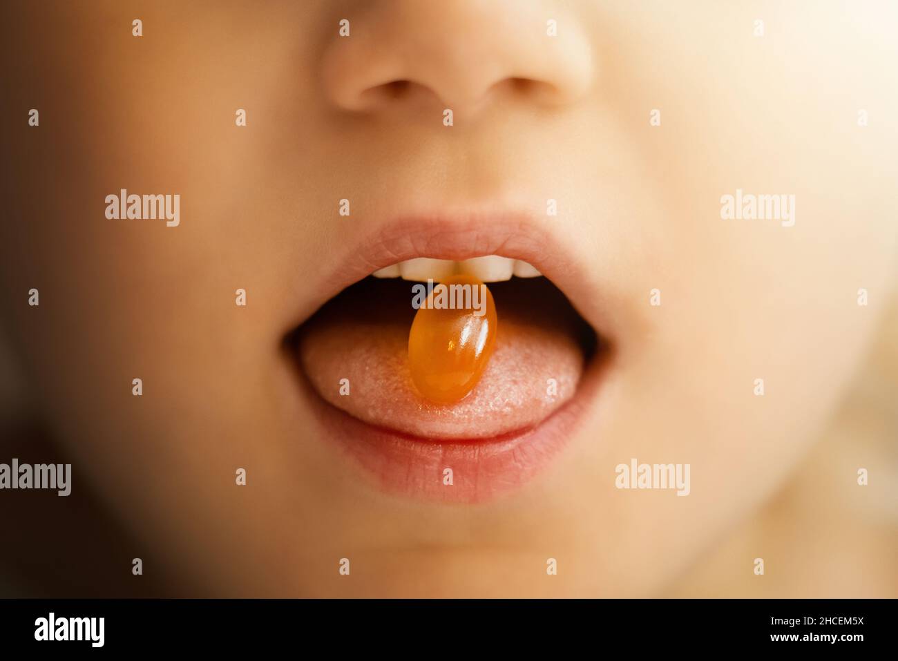 child takes omega 3 capsule. mouth closeup with fish oil pill. dietary supplements Stock Photo