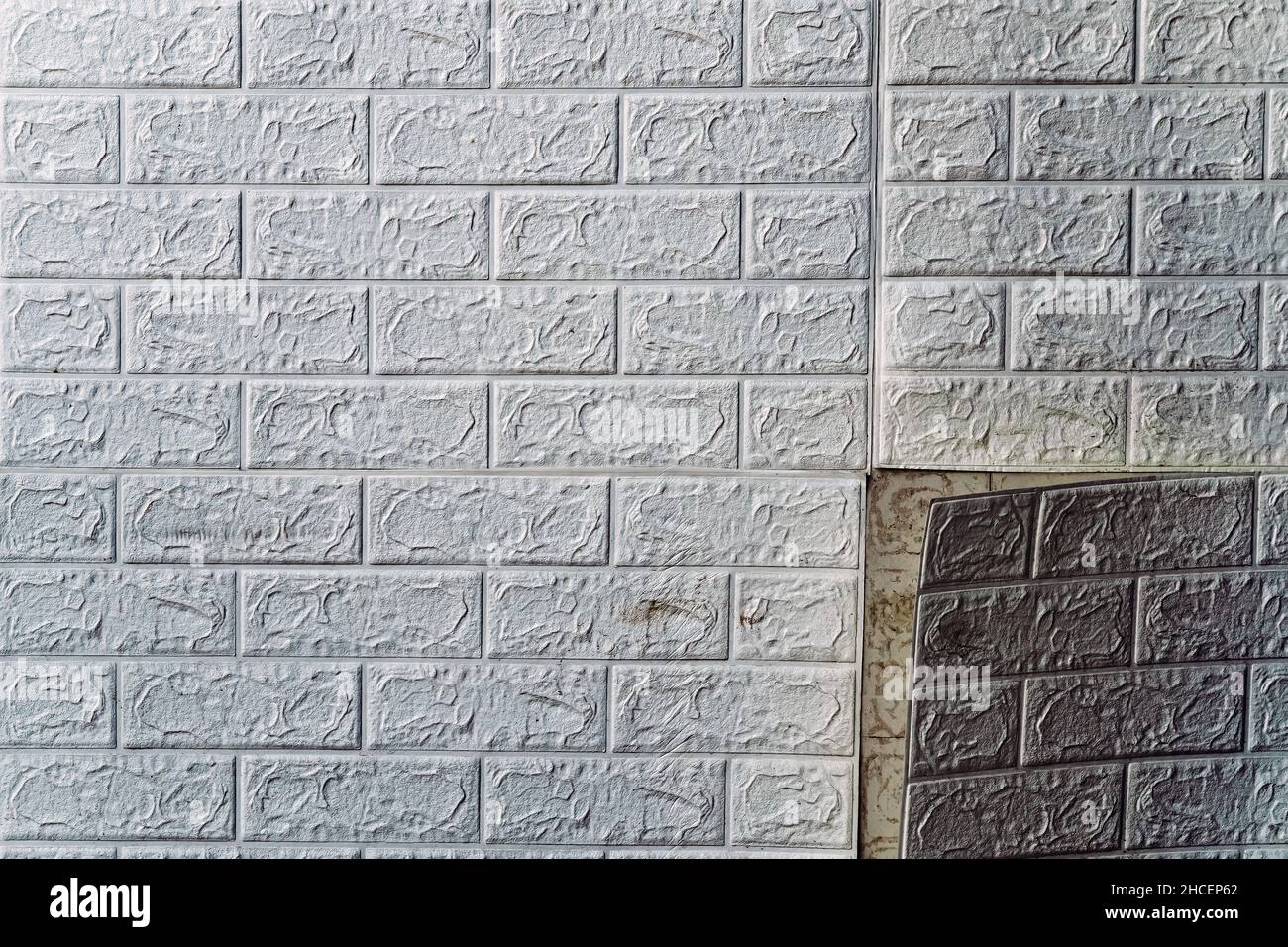 The wallpaper begins to peel off. Old white bricks wallpaper peeled off from the wall inside the