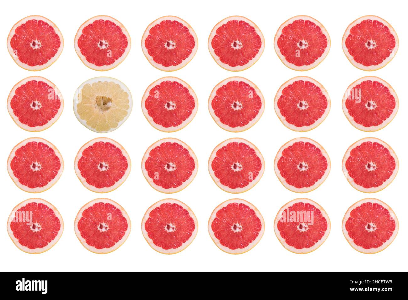 Rows of grapefruit slices and only one pomelo slice isolated on a white background Stock Photo