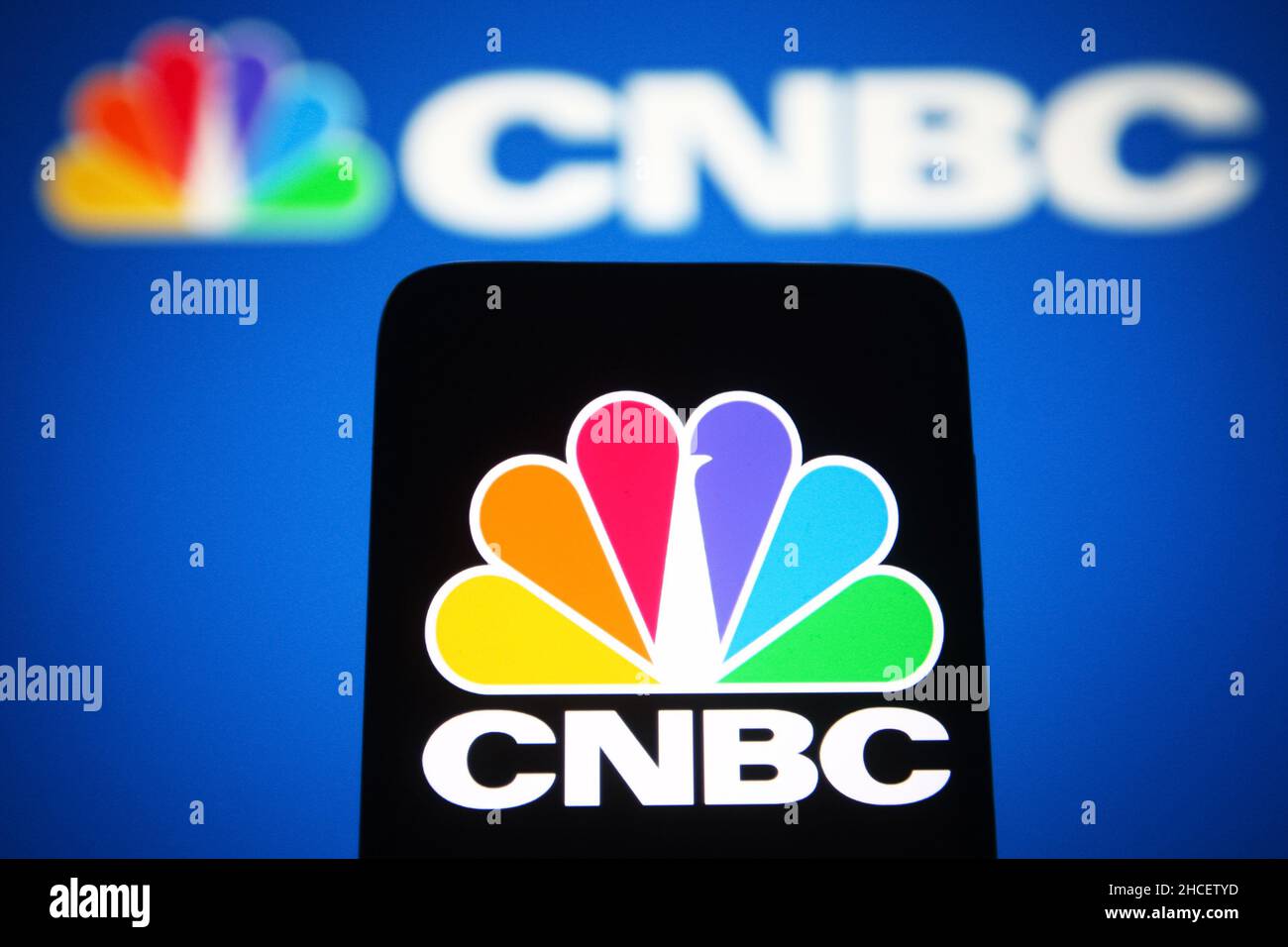 In this photo illustration, CNBC (Consumer News and Business Channel) logo is seen on a smartphone and in the background. Stock Photo