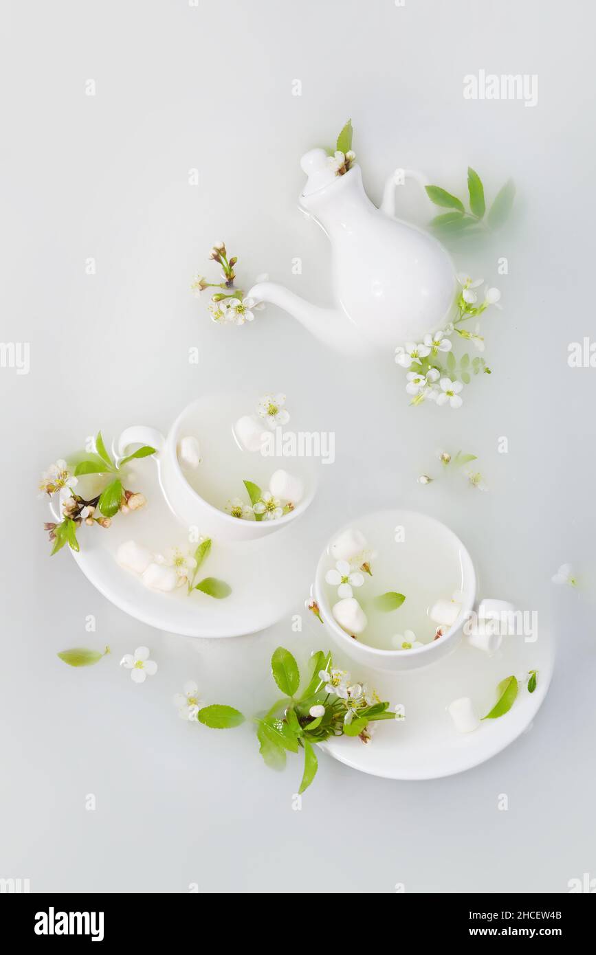 White teapot and tea cups with cherry flowers , leaves Stock Photo