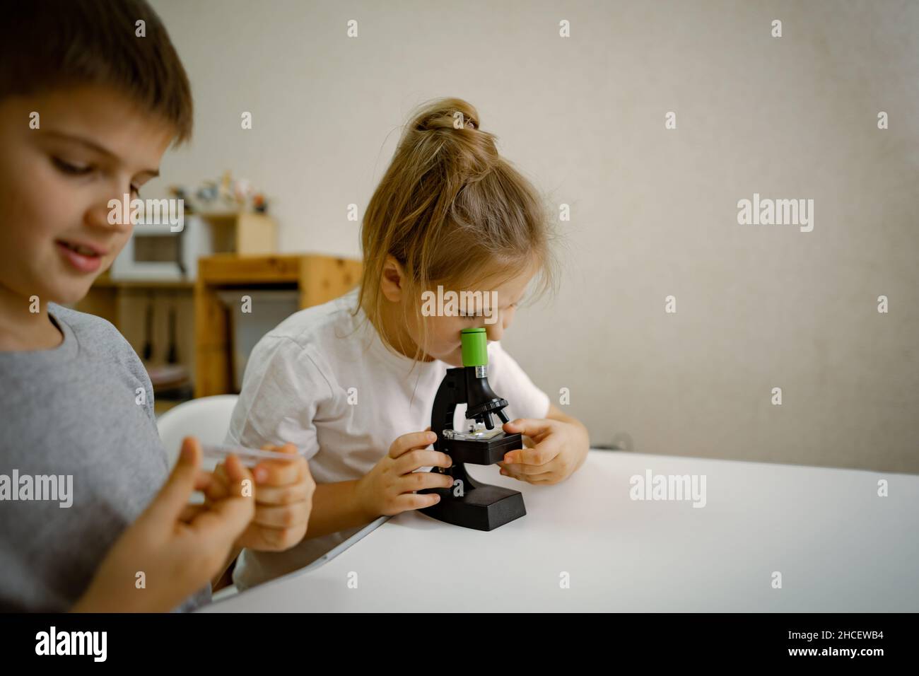 Children, girl and boy at home in the room look through microscope Stock Photo