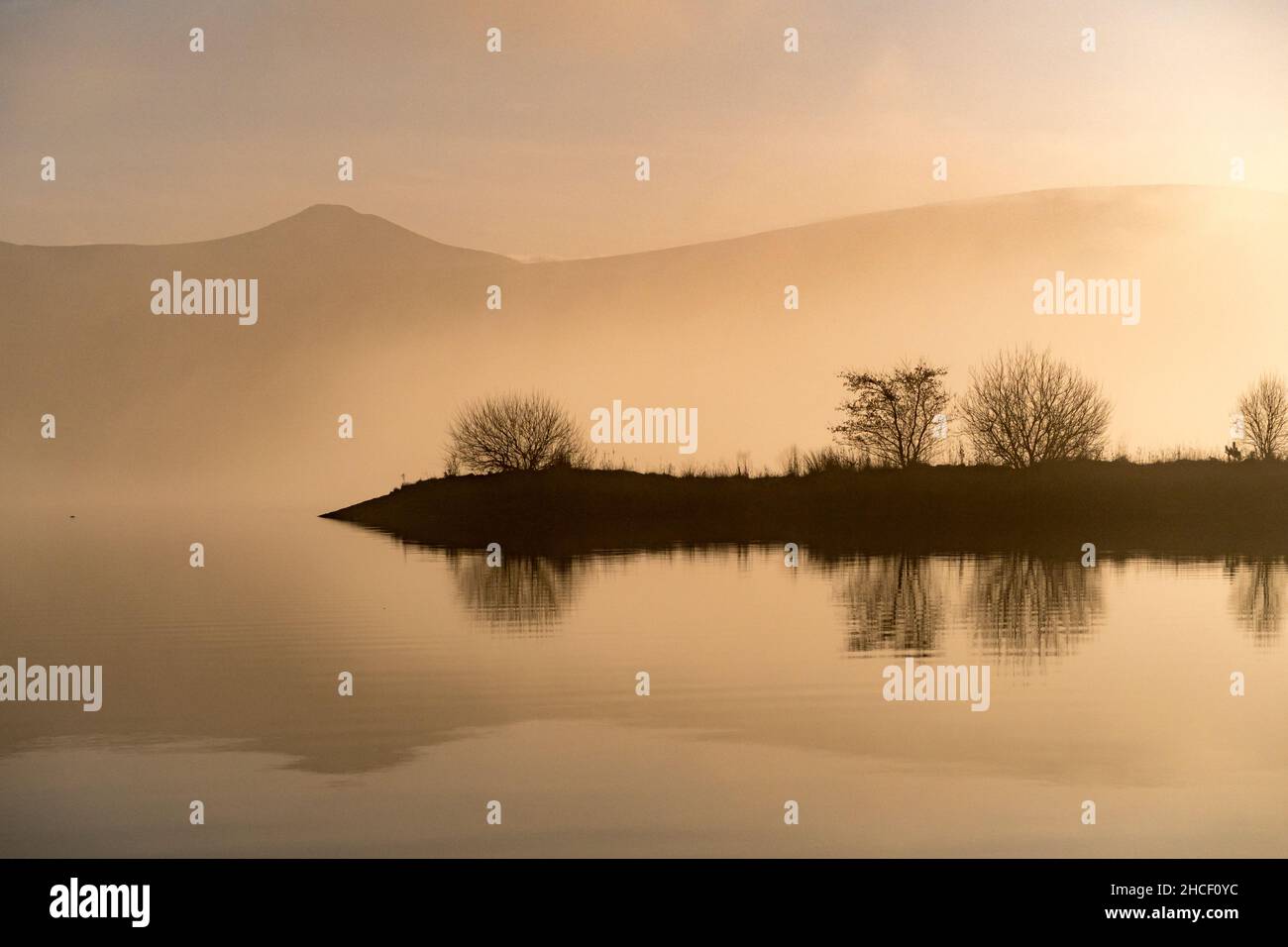 Hills and clouds reflected in the water of reservoir on a winter day Stock Photo