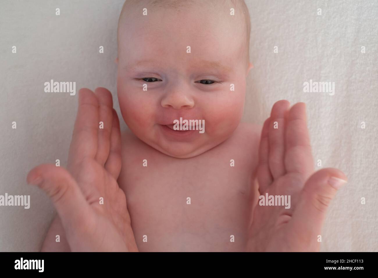 Adorable newborn infant baby girl smiling to his parent Stock Photo