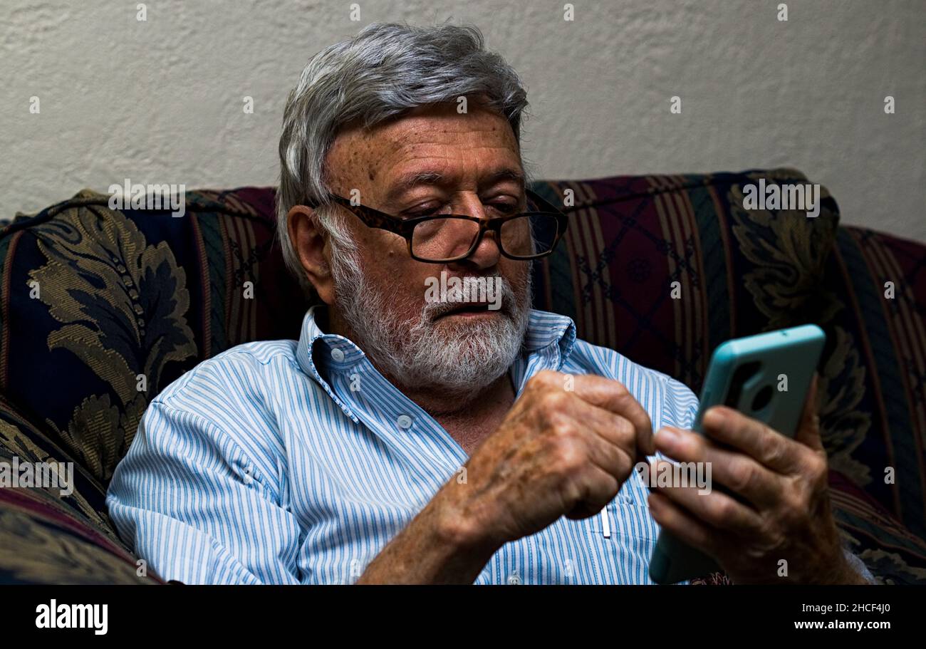 Old man messing with a phone Stock Photo