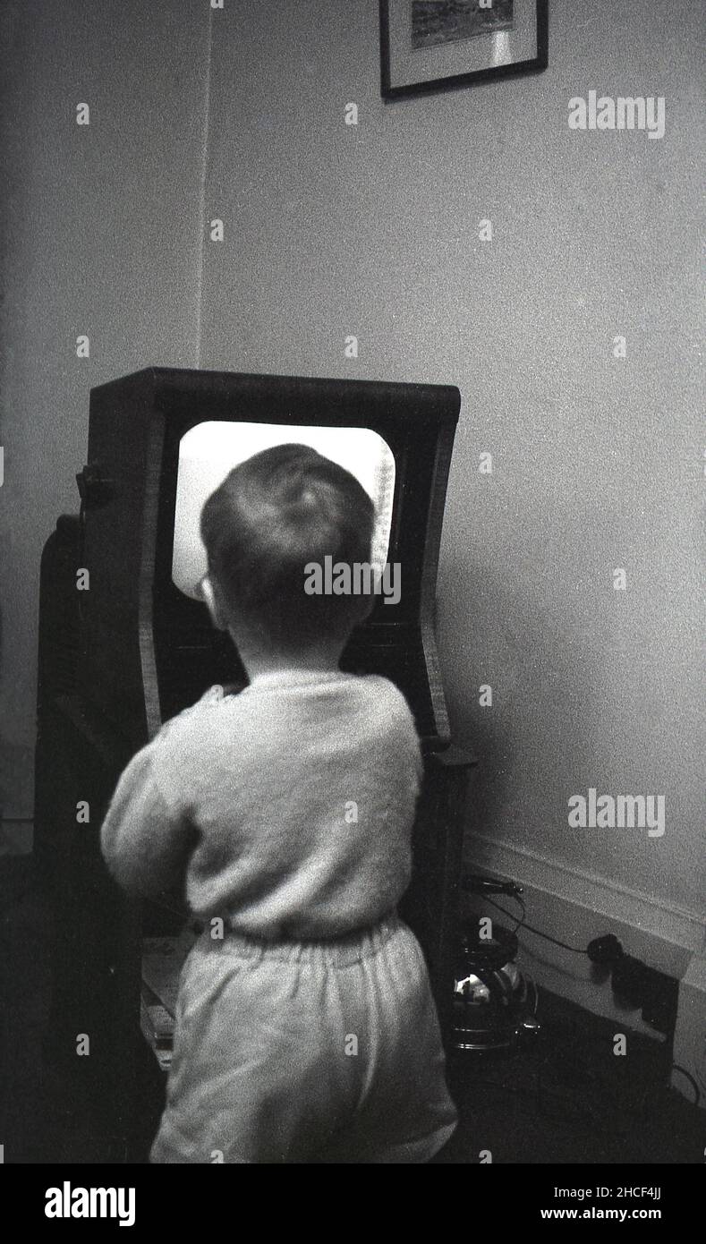 Late 1950s, historical, a little boy standing close-up to a small television set of the era watching a programme, England, UK. In 1950, a television set was a luxury item, with only around 350,000 British households owning one. but by the end of the decade, nearly 75% of the population had television. Stock Photo