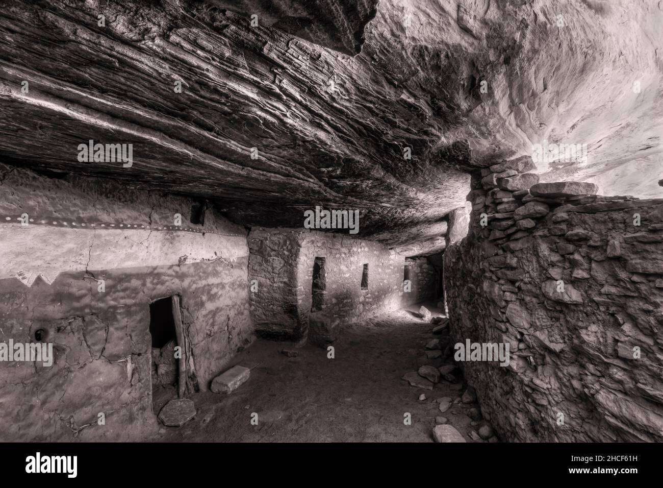 An interior hallway below a sloping layered cliff wall in the Moon House in McCloyd Canyon, Bears Ears National Monument. (Black & White) Stock Photo