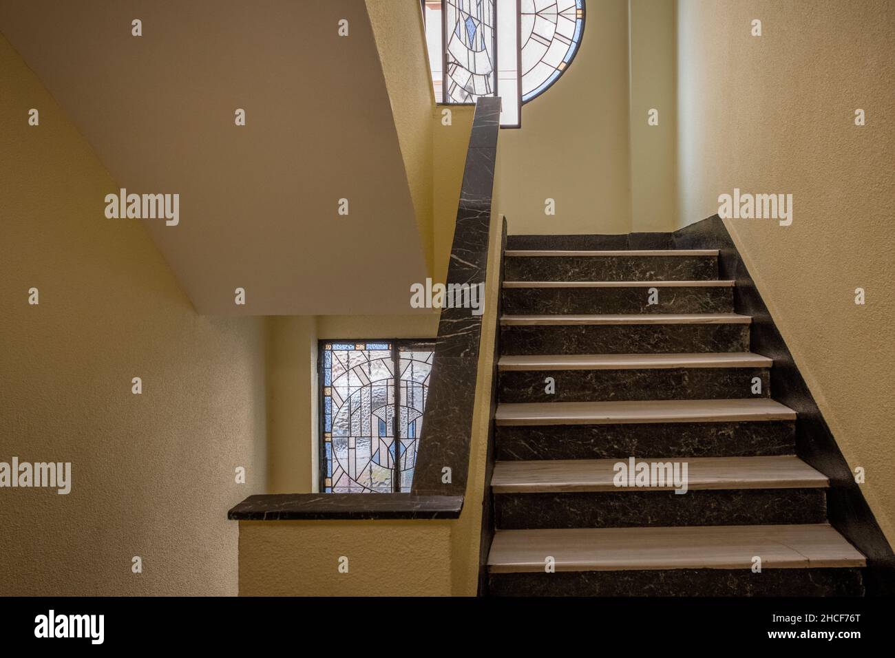 Marble stairs between the floors of a building with old leaded windows Stock Photo