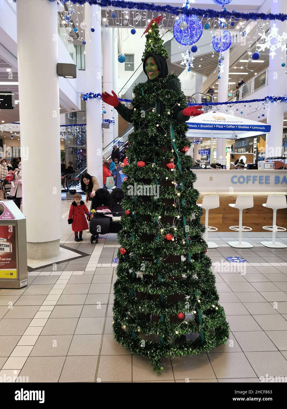A vertical shot of a lady dressed up like a Christmas tree on stilts entertaining children in Belfast, UK Stock Photo