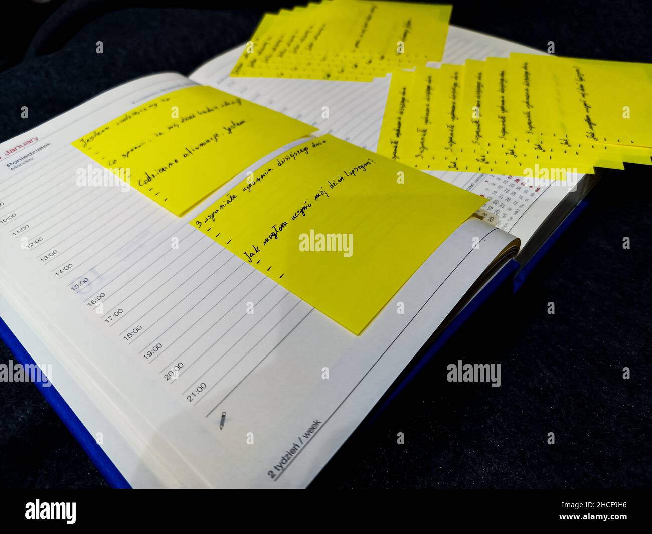 Opened book calendar and daily planner with hours and lines of a day full of yellow sticky notes with writings on it Stock Photo