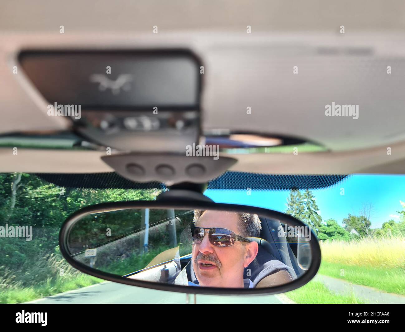 Back view of male driver looking at rearview mirror in car Stock Photo ...