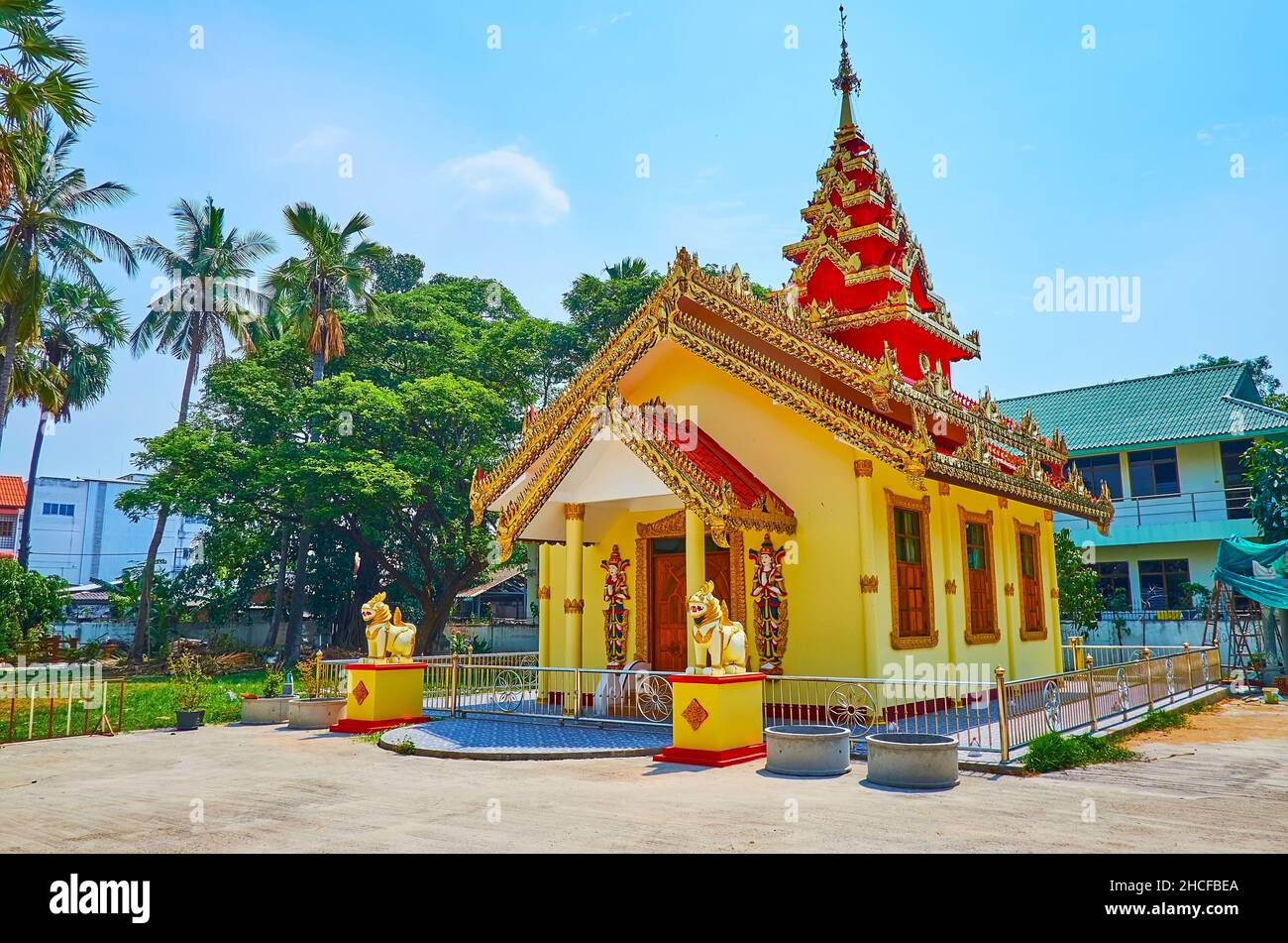 The facade of the scenic Burmese style Ubosot of Wat Sai Moon Myanmar temple, decorated with tall pyathat tower, gable roof, carved gilt bargeboards, Stock Photo