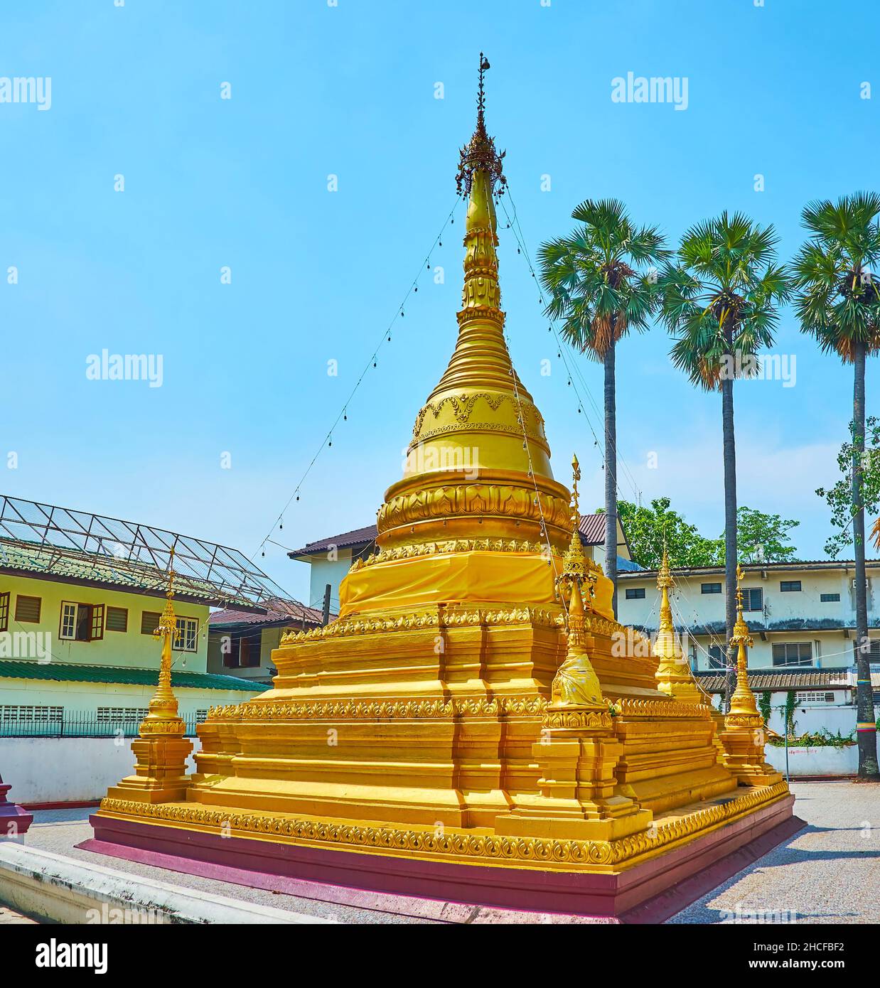 The golden Chedi of Wat Sai Moon Myanmar temple is topped with beautiful hti umbrella and surrounded with mini chedis, connected with the top of the m Stock Photo