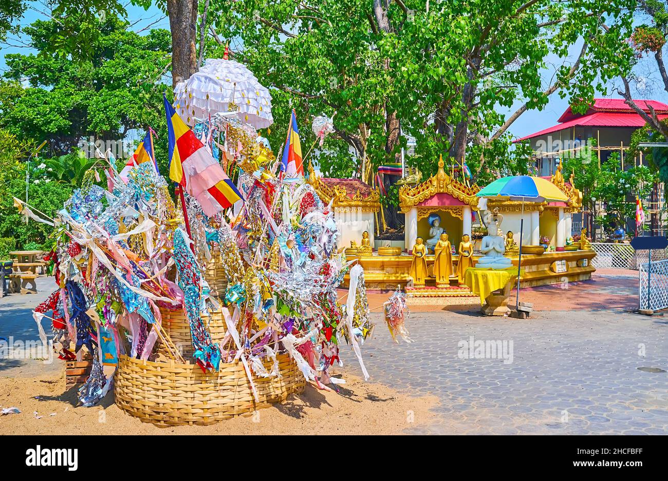 The courtyard of Wat Sai Moon Myanmar temple with sculptures around the Bodhi Tree and the small wicker wooden stupa (chedi) with colorful garlands, f Stock Photo