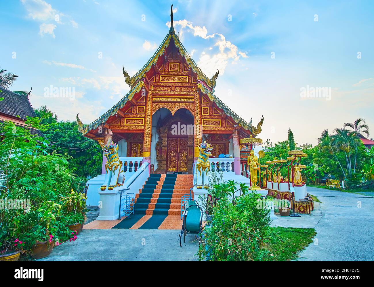 The facade of the scenic historic Viharn of Wat Puak Hom with gable (pyathat) roof, Singha lion sculptures, Naga serpents on bargeboards and gilt patt Stock Photo
