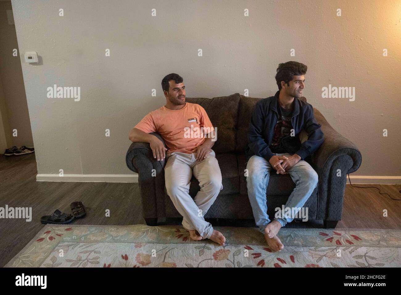 Austin, TX, USA. 2nd Oct, 2021. Two single Afghan men lounge in their sparse apartment in north Austin. For three months, refugees fleeing turmoil in Afghanistan continue to be resettled in Texas with many single men, large families with children scatttered amongst dozens of apartments in Austin, Texas. Faith-based groups have stepped up to coordinate efforts in furnishing homes for hundreds of refugees. (Credit Image: © Bob Daemmrich/ZUMA Press Wire) Stock Photo