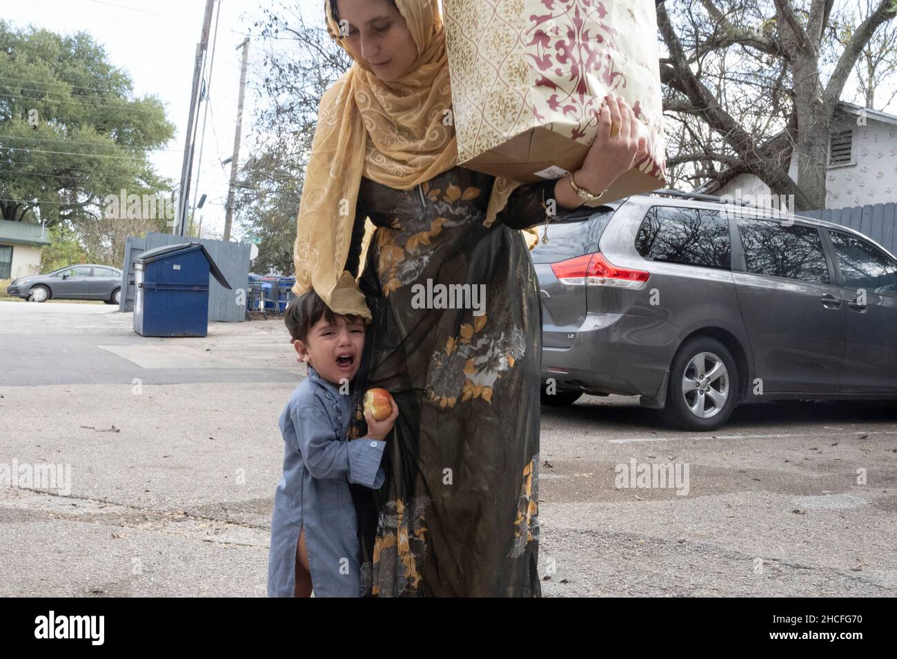 Austin, TX, USA. 19th Dec, 2021. An Afghan woman tries to comfort her crying child in south Austin. For three months, refugees fleeing turmoil in Afghanistan continue to be resettled in Texas with many single men, large families with children scatttered amongst dozens of apartments in Austin, Texas. Faith-based groups have stepped up to coordinate efforts in furnishing homes for hundreds of refugees. (Credit Image: © Bob Daemmrich/ZUMA Press Wire) Stock Photo