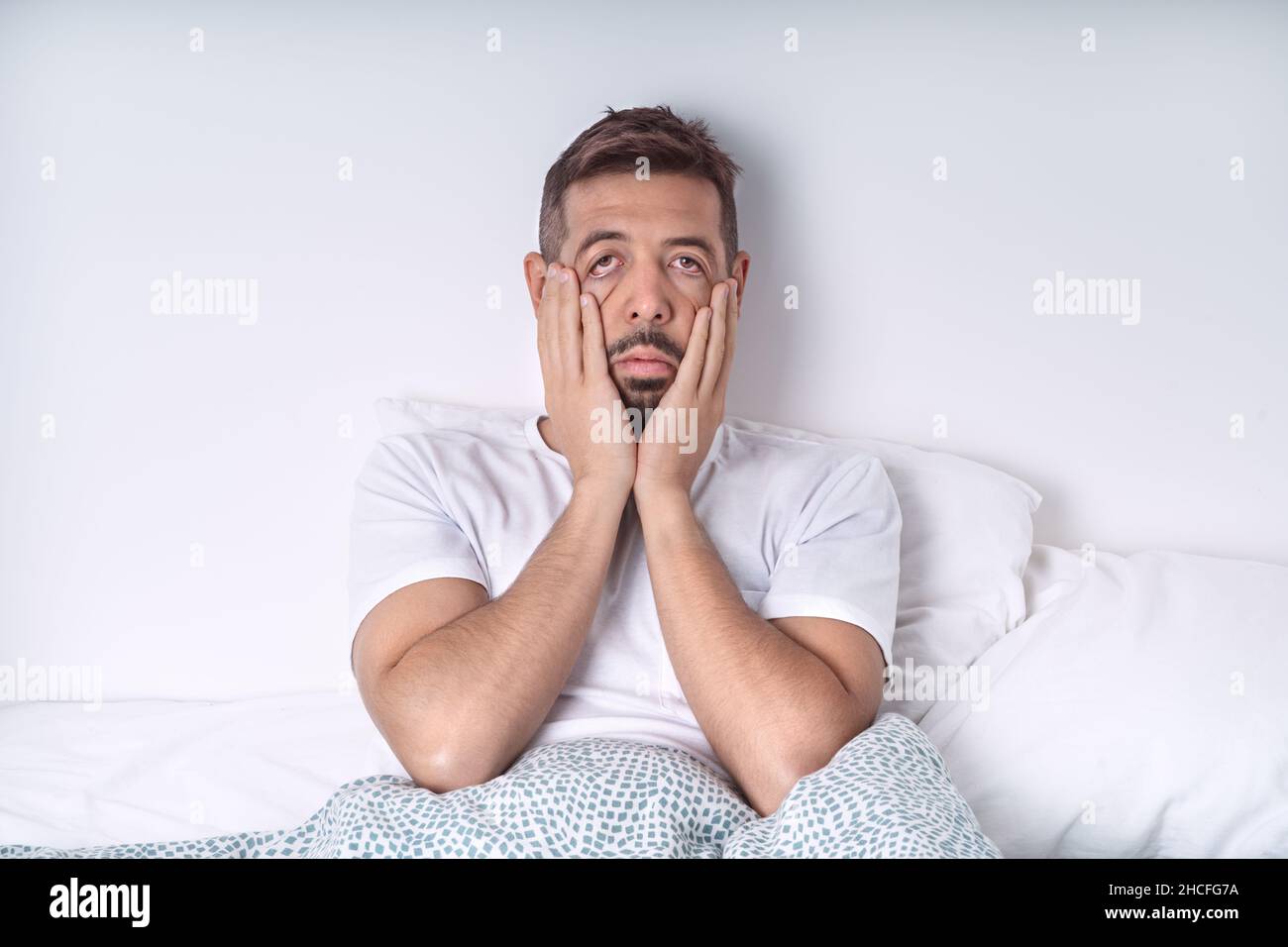 Stressed and depressed man lying in the bed. Bad mood and bad morning. Stock Photo