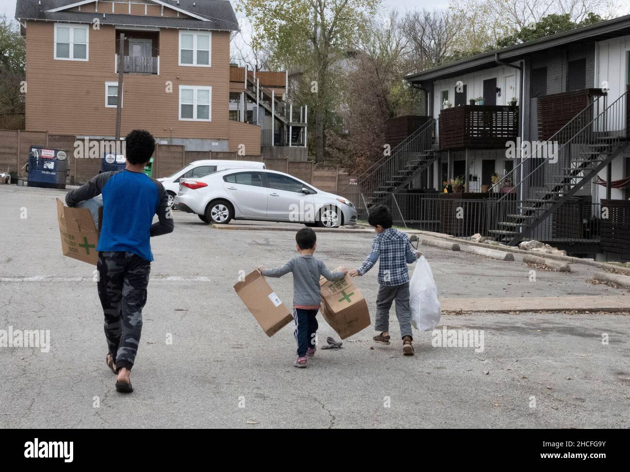 Austin, TX, USA. 19th Dec, 2021. Afghan boys take out the trash from their apartment. For three months, refugees fleeing turmoil in Afghanistan continue to be resettled in Texas with many single men, large families with children scatttered amongst dozens of apartments in Austin, Texas. Faith-based groups have stepped up to coordinate efforts in furnishing homes for hundreds of refugees. (Credit Image: © Bob Daemmrich/ZUMA Press Wire) Stock Photo