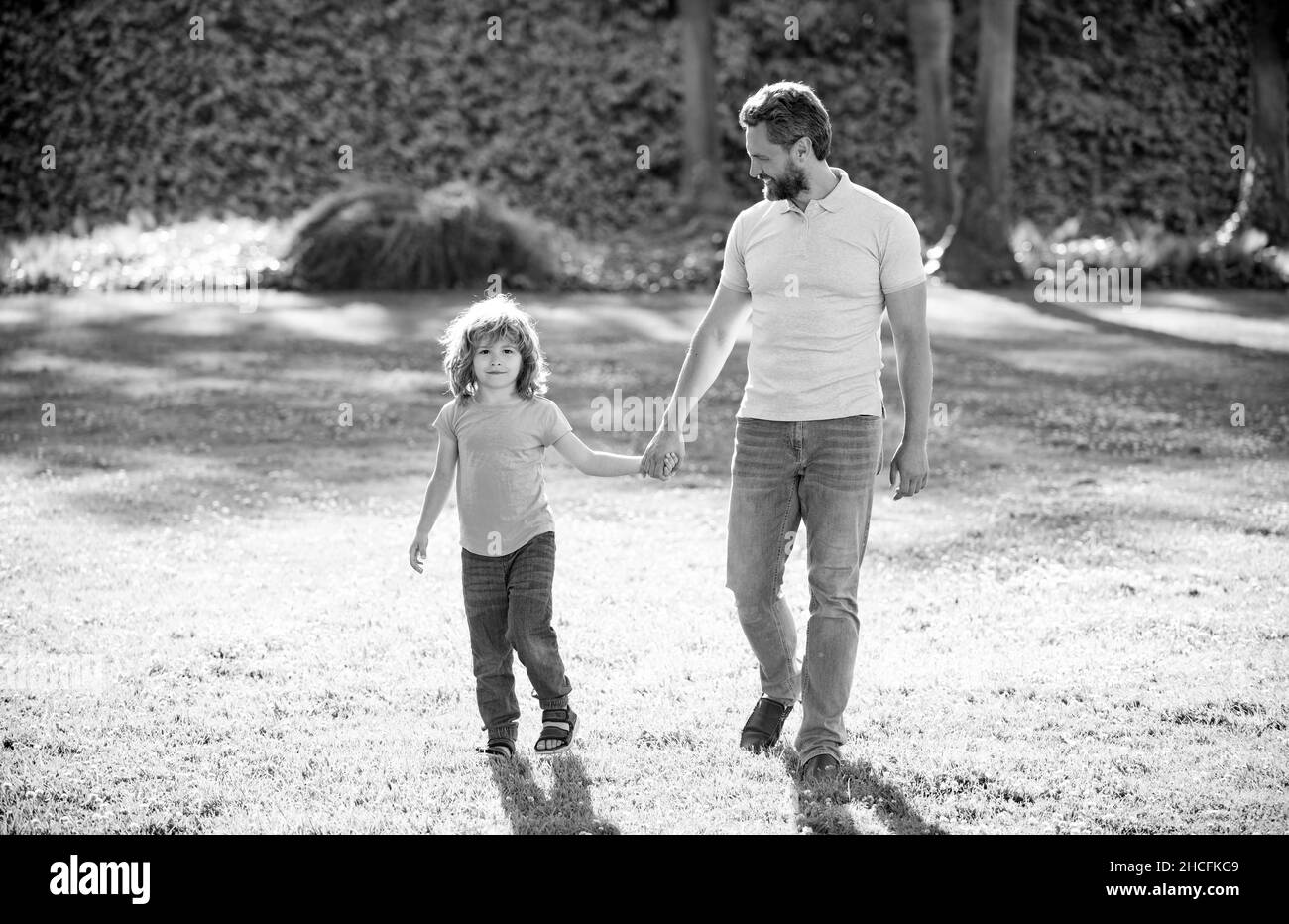 happy family value. childhood and parenthood. parent leads little child boy on grass. Stock Photo
