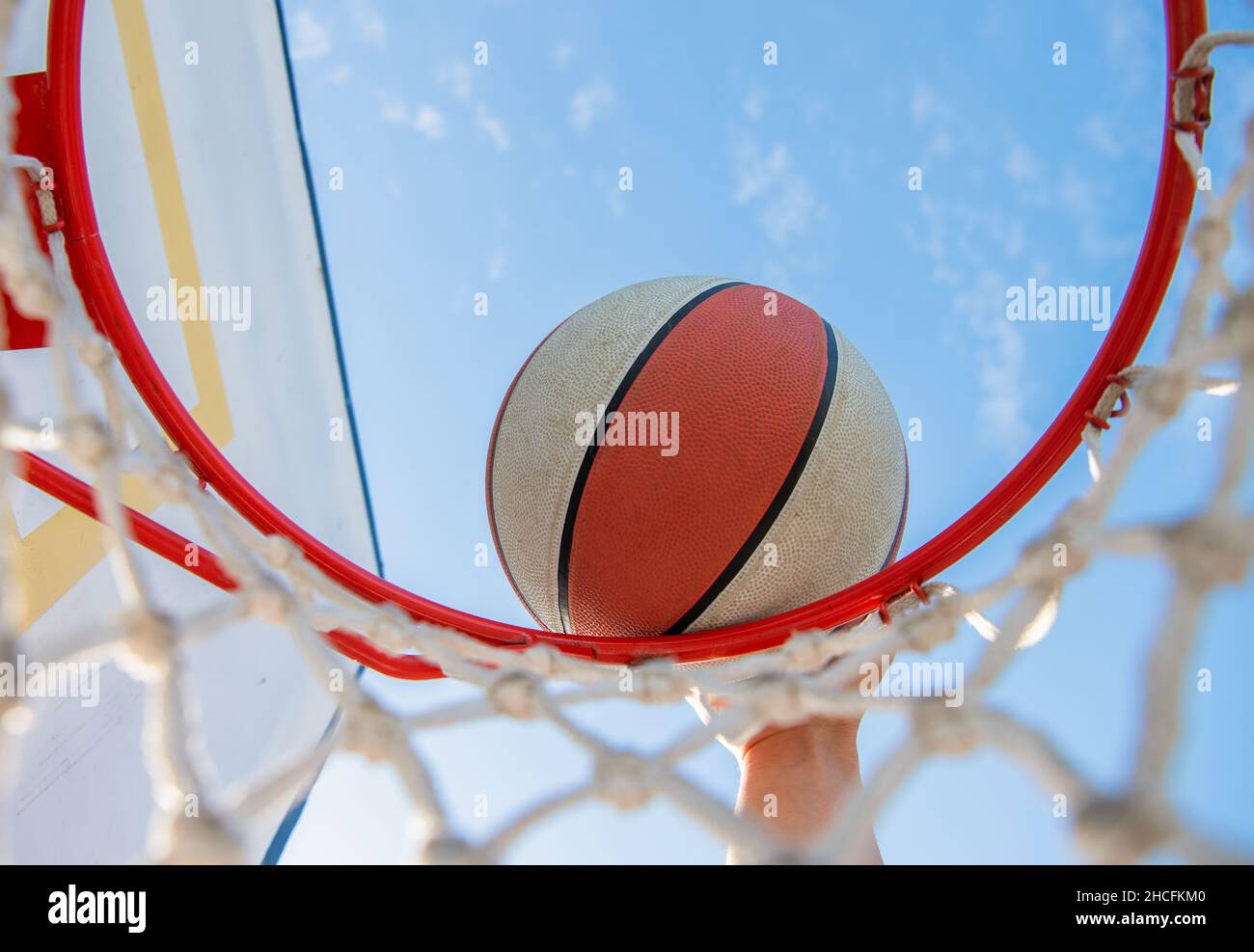 dunking basketball ball through net ring with hand, basketball Stock Photo
