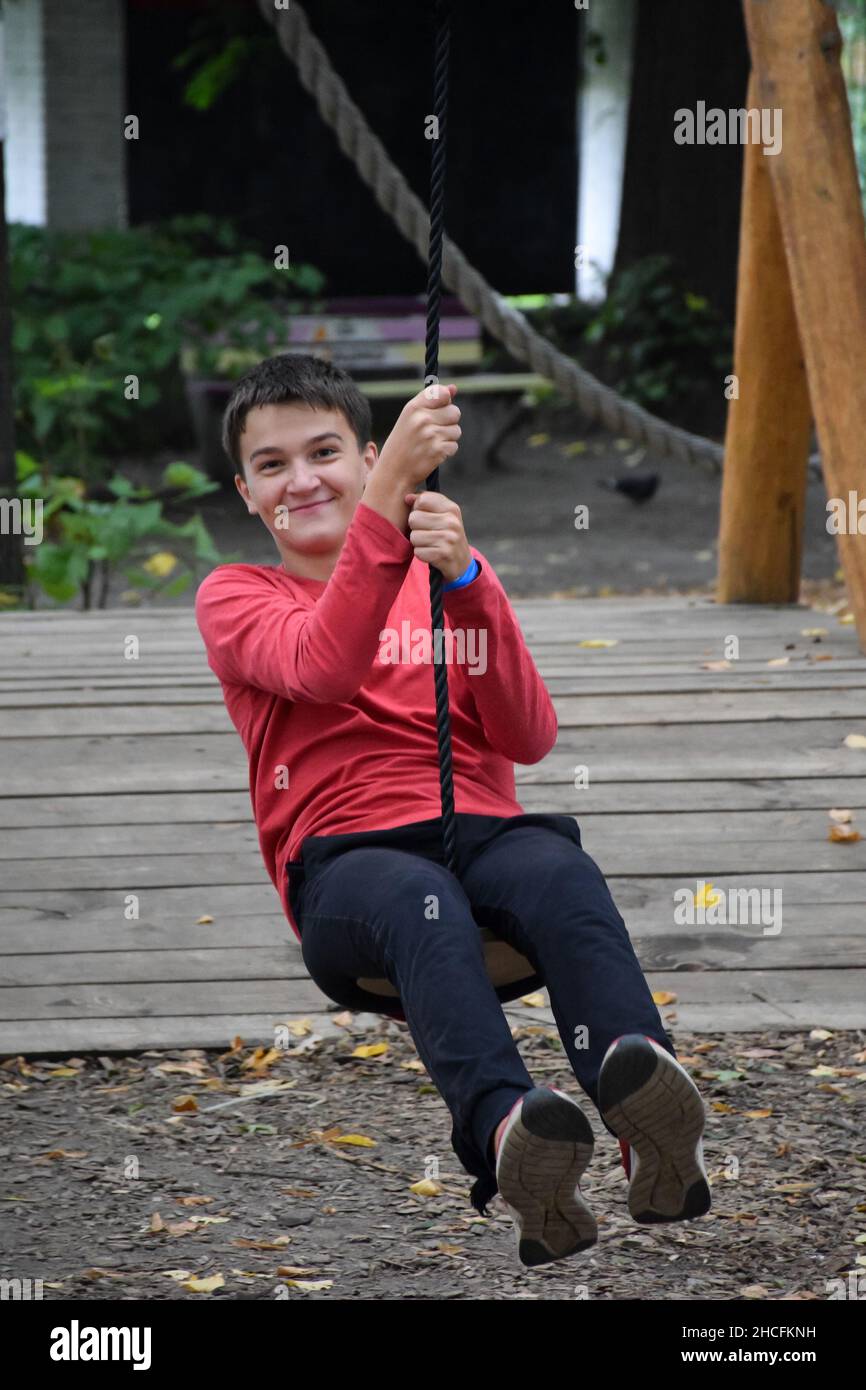 Young attractive guy descends on a zipline in an amusement park and smiles Stock Photo